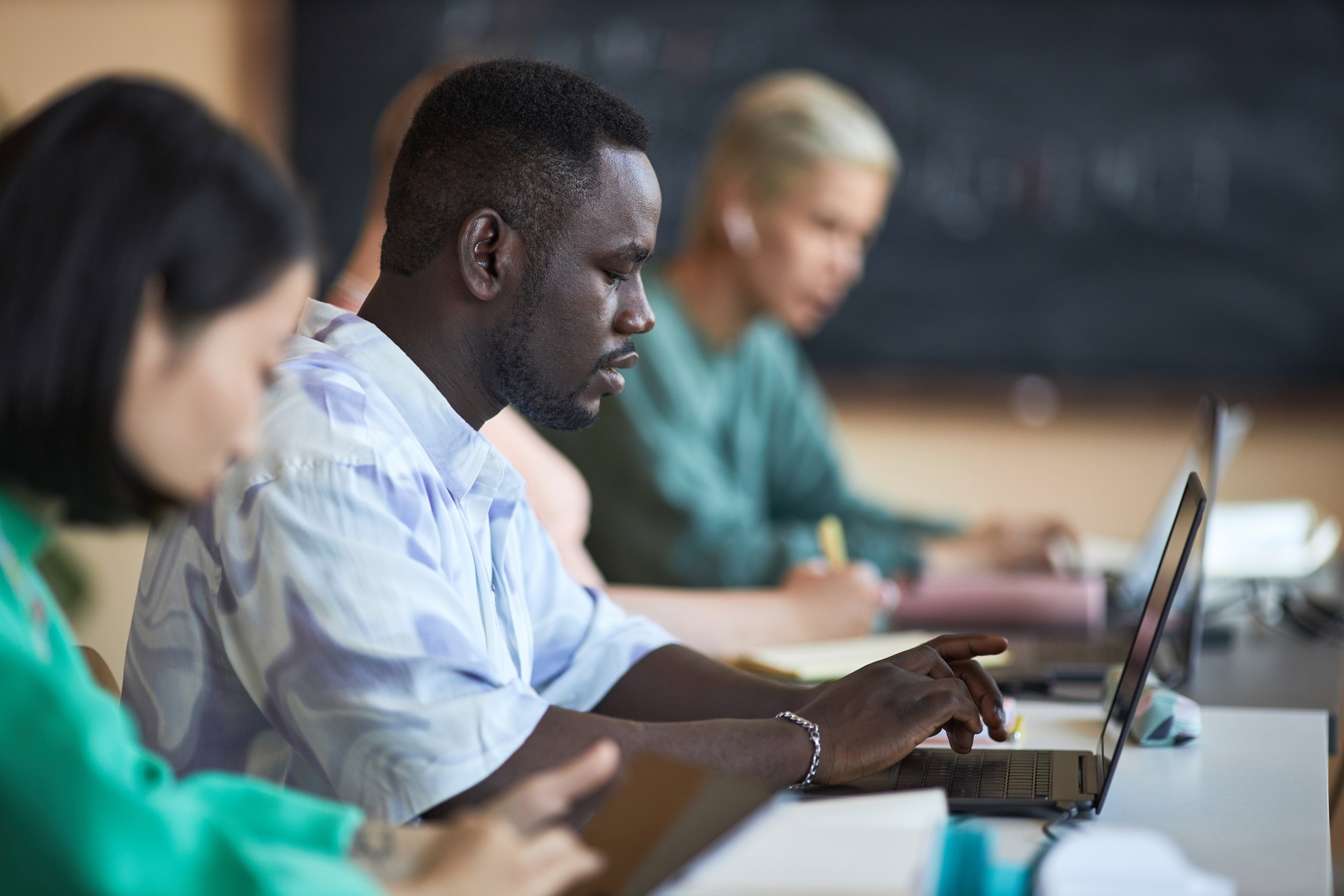 Side view of young African American student of highschool using laptop